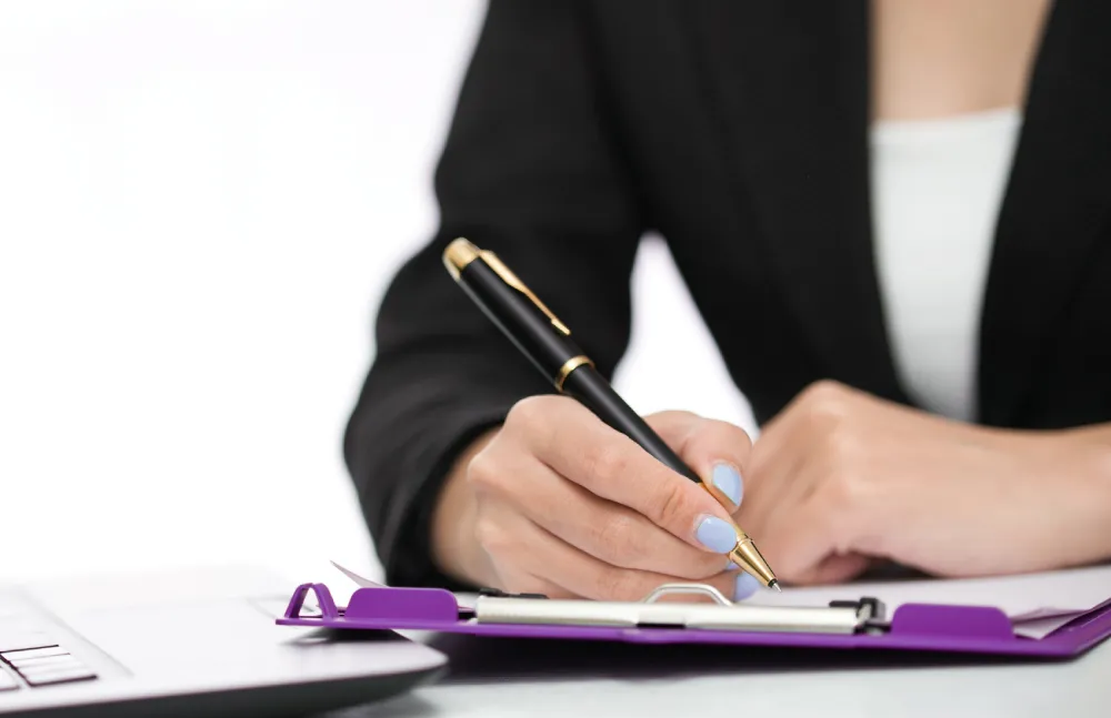 Femme en veste noire prenant des notes sur un clipboard avec un stylo