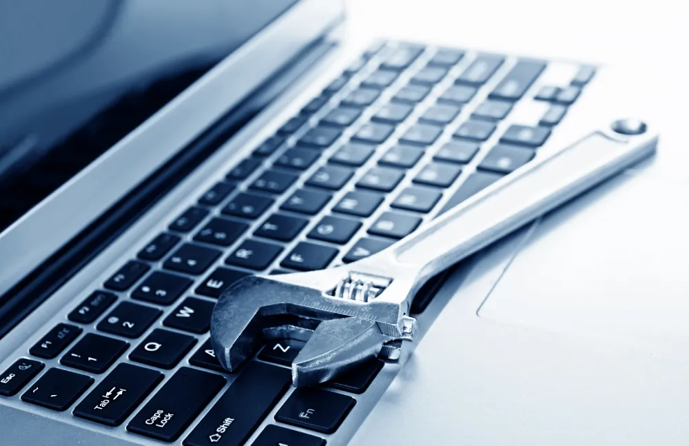 Clé à molette et clé plate posées sur un clavier d'ordinateur portable