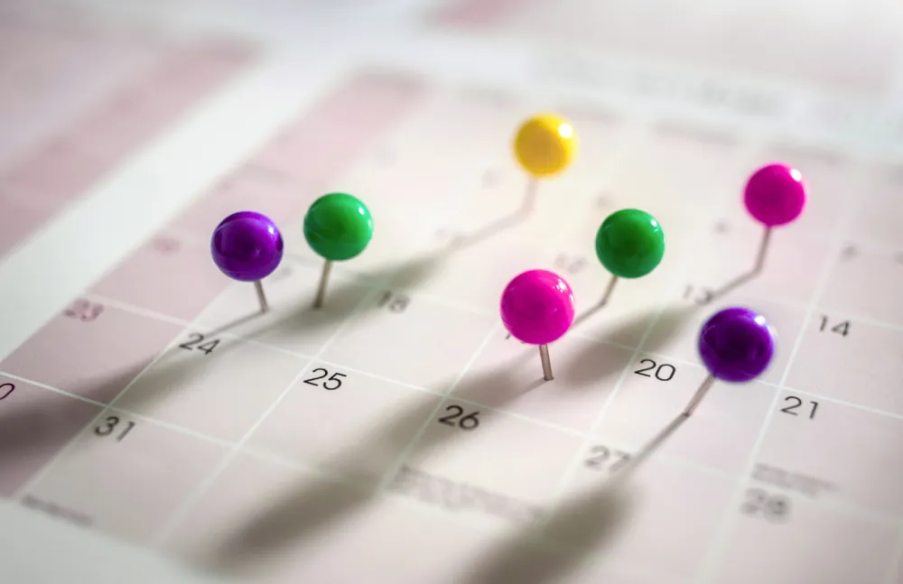 Épingles colorées plantées sur un calendrier pour planifier une stratégie éditoriale