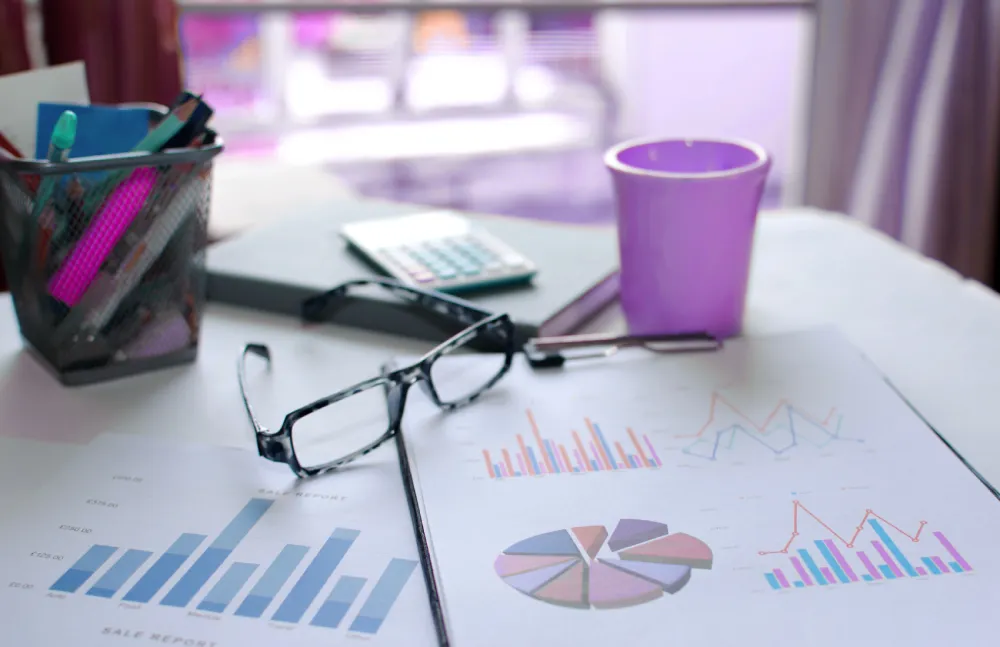 Bureau avec des rapports de graphiques et tableaux, lunettes, calculatrice et tasse violette