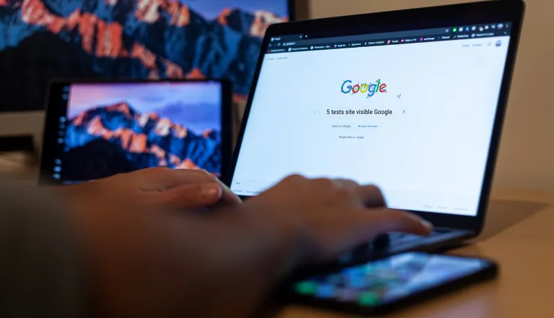main d'homme qui va taper une requête sur Google : 5 tests gratuits site visible Google