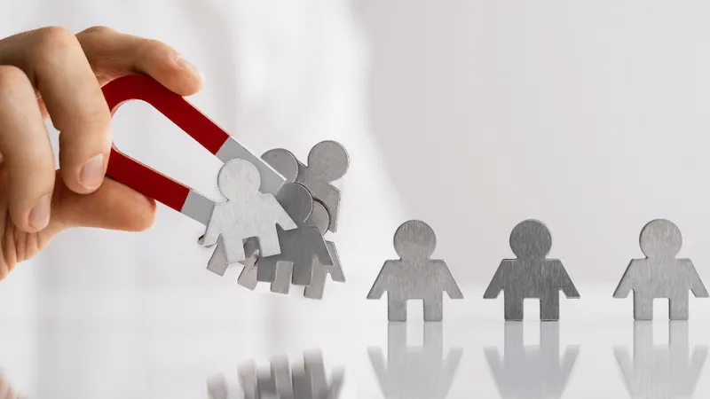 aimant qui attirer des personnages en métal pour illustrer l'article attirer des clients sur sont site web sans publicité
