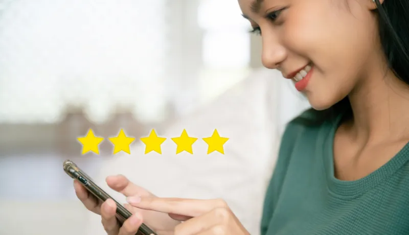 femme qui tient un téléphone et qui met 5 étoiles à son avis client