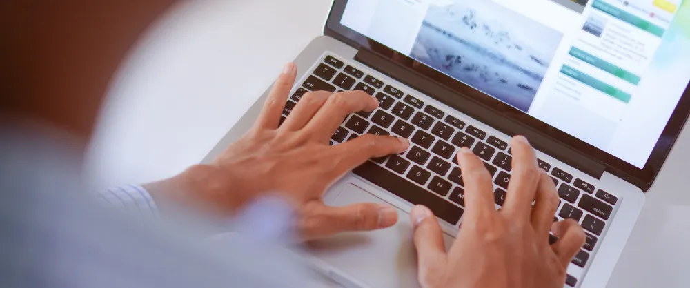 mains d'homme sur un clavier pour symboliser la rédaction de page locale