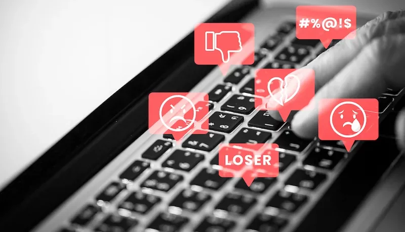 clavier noir avec des icônes négatifs comme un pouce baissé, le mot loser, un émoji mécontent pour symboliser les faux avis clients négatifs